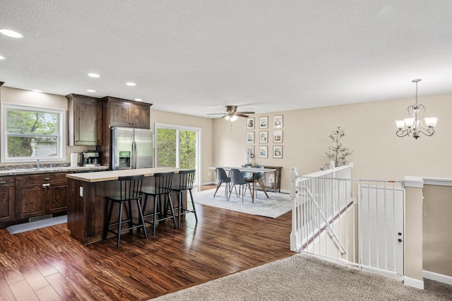 1002 8th Ave N, Princeton, MN 55371 - kitchen with stainless steel fridge, a kitchen island, a kitchen breakfast bar, dark brown cabinets, and plenty of natural light