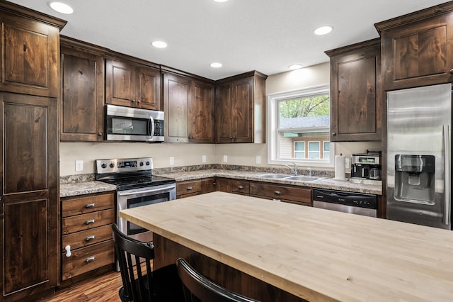 1002 8th Ave N, Princeton, MN 55371 - kitchen with stainless steel appliances, a sink, wooden counters, dark brown cabinets, and wood finished floors