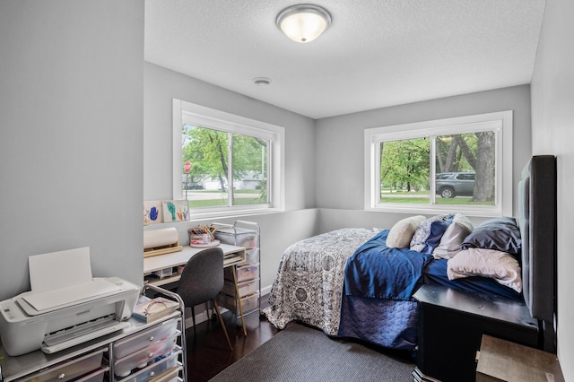 1002 8th Ave N, Princeton, MN 55371 - bedroom with multiple windows, a desk, a textured ceiling, and wood finished floors