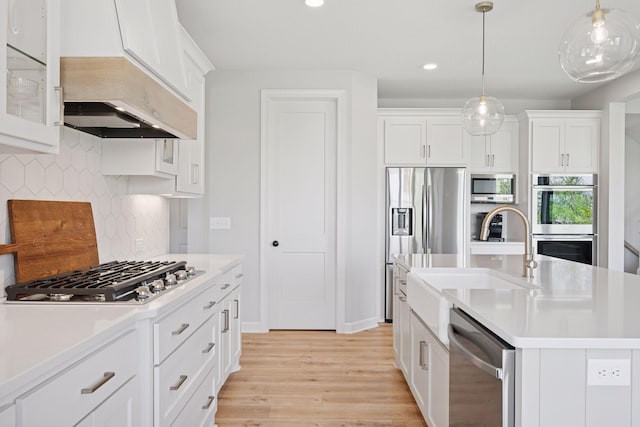 kitchen featuring stainless steel appliances, a sink, light wood-type flooring, light countertops, and backsplash
