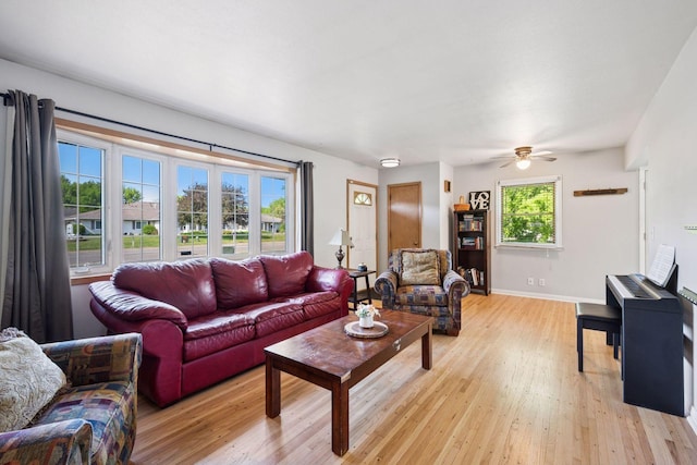 living room with light wood finished floors, ceiling fan, and baseboards