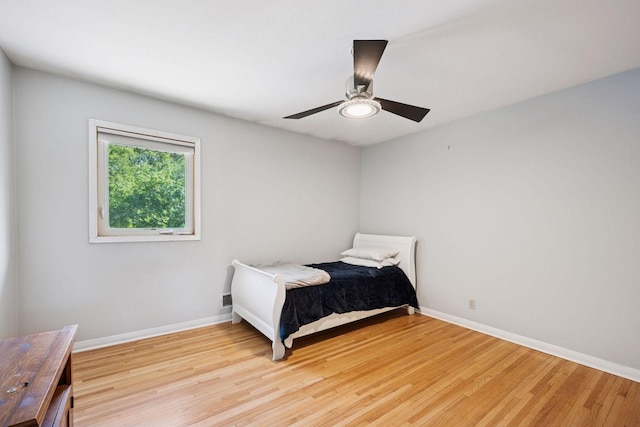 bedroom with light wood-type flooring, baseboards, and a ceiling fan