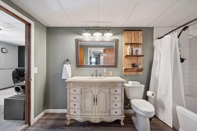 full bath with wood finished floors, a paneled ceiling, toilet, baseboards, and vanity
