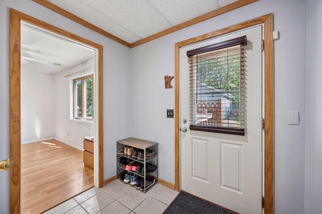 doorway featuring light tile patterned flooring, baseboards, and crown molding