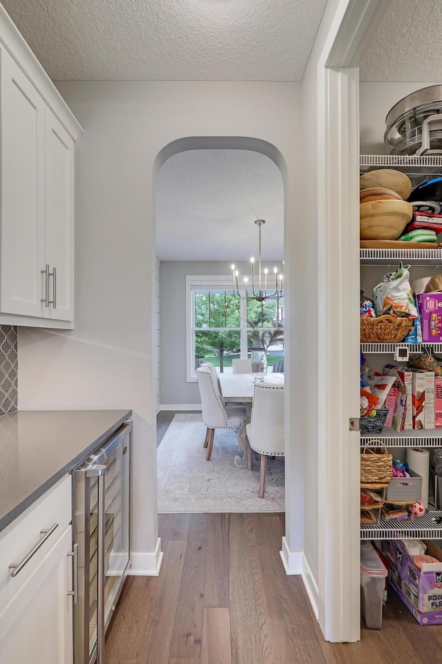 14778 50th St NE, Saint Michael, MN 55376 - corridor featuring arched walkways, wine cooler, dark wood-style floors, a textured ceiling, and baseboards