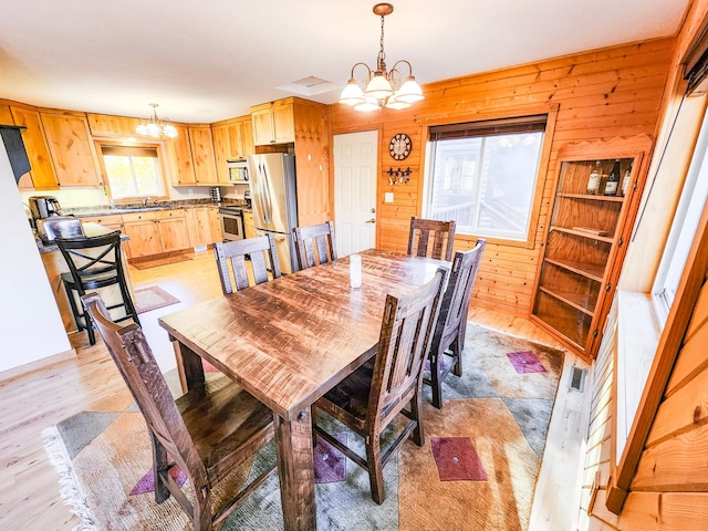 1910 Longwood Point Rd NE, Outing, MN 56662 - dining area with a chandelier, wooden walls, and light wood finished floors