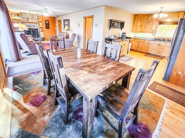 1910 Longwood Point Rd NE, Outing, MN 56662 - dining space featuring light wood-style flooring, ceiling fan, a fireplace, and a chandelier