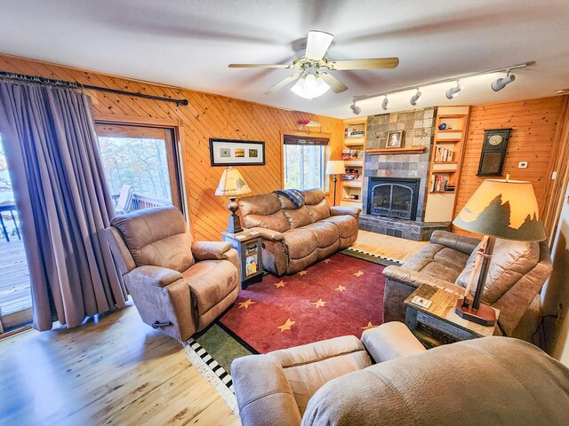 1910 Longwood Point Rd NE, Outing, MN 56662 - living room featuring wood finished floors, a tiled fireplace, wood walls, and a ceiling fan