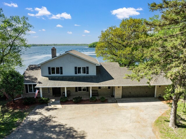 14490 Irwin Ct, Montgomery, MN 56069 - view of front facade featuring asphalt driveway, an attached garage, a porch, and a water view
