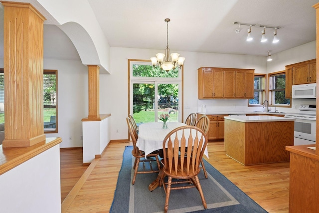 1780 Quail Dr, Shakopee, MN 55379 - dining space featuring light wood-style floors, a chandelier, arched walkways, baseboards, and decorative columns