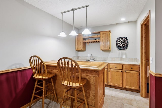 1780 Quail Dr, Shakopee, MN 55379 - kitchen featuring a sink, a textured ceiling, a breakfast bar, pendant lighting, and light tile patterned floors