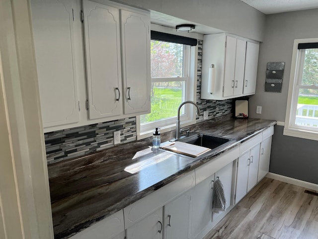 603 Main Ave N, Roseau, MN 56751 - kitchen featuring a sink, white cabinets, decorative backsplash, and light wood-style flooring