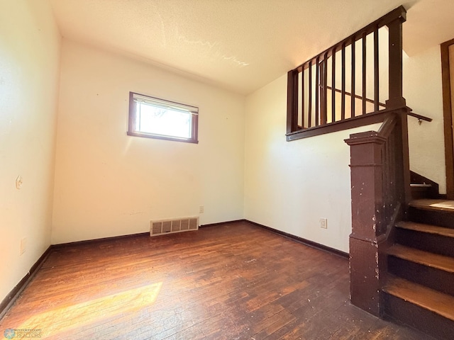 empty room with wood-type flooring, stairway, and baseboards