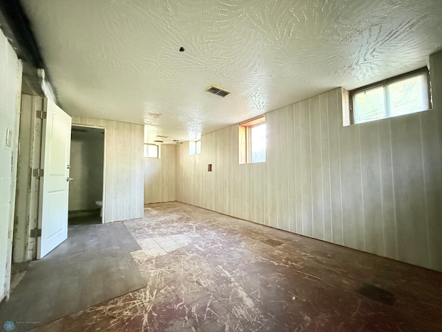 below grade area featuring wood walls and a textured ceiling