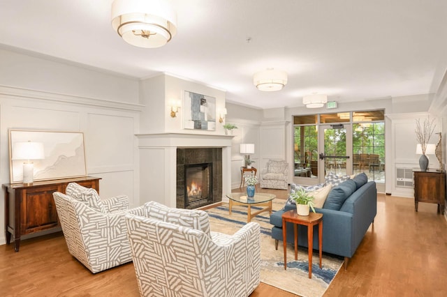 living room featuring a decorative wall, light wood finished floors, a fireplace, and ornamental molding