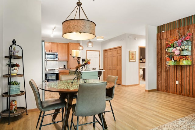 dining area with light wood finished floors and baseboards