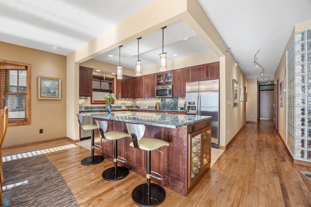 300 Broadway N Unit 204, Fargo, ND 58102 - kitchen with appliances with stainless steel finishes, light wood-style flooring, baseboards, backsplash, and a kitchen bar