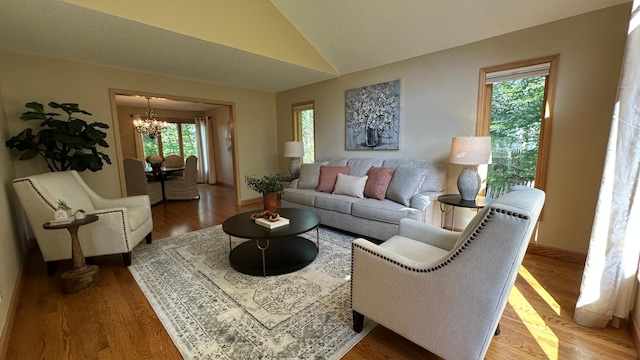 living area with a chandelier, vaulted ceiling, wood finished floors, and baseboards