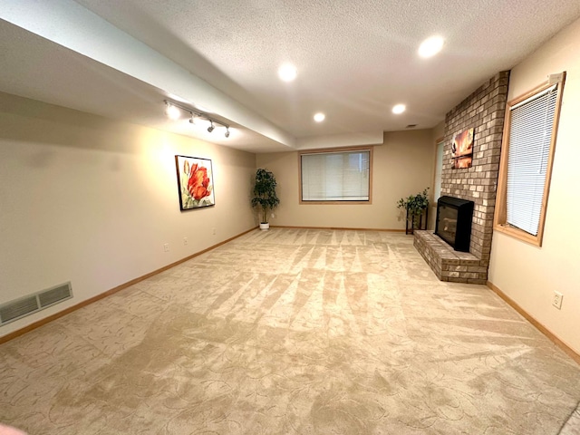 below grade area featuring light colored carpet, a brick fireplace, a textured ceiling, recessed lighting, and baseboards