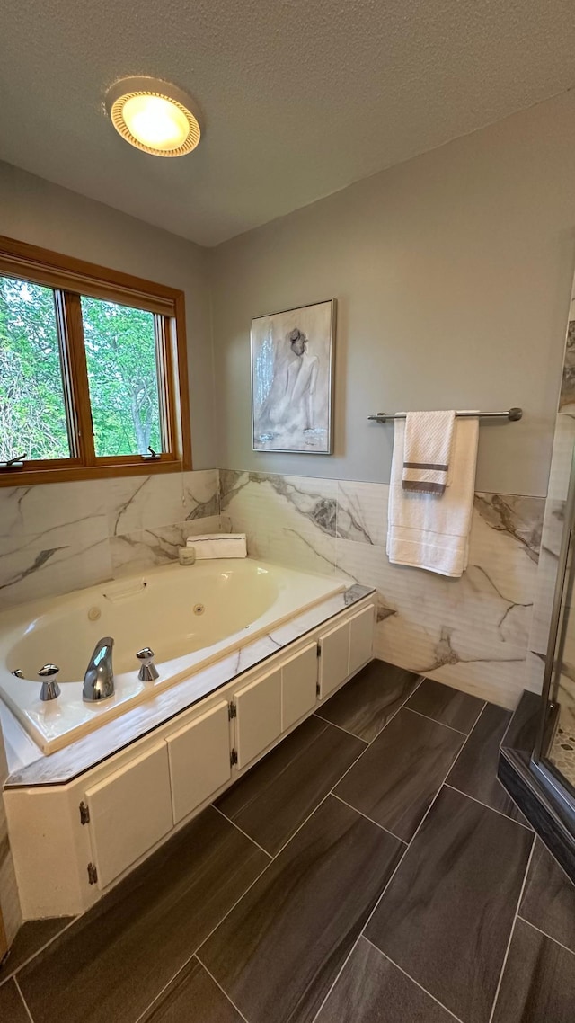bathroom with tile walls, a tub with jets, wainscoting, and a stall shower