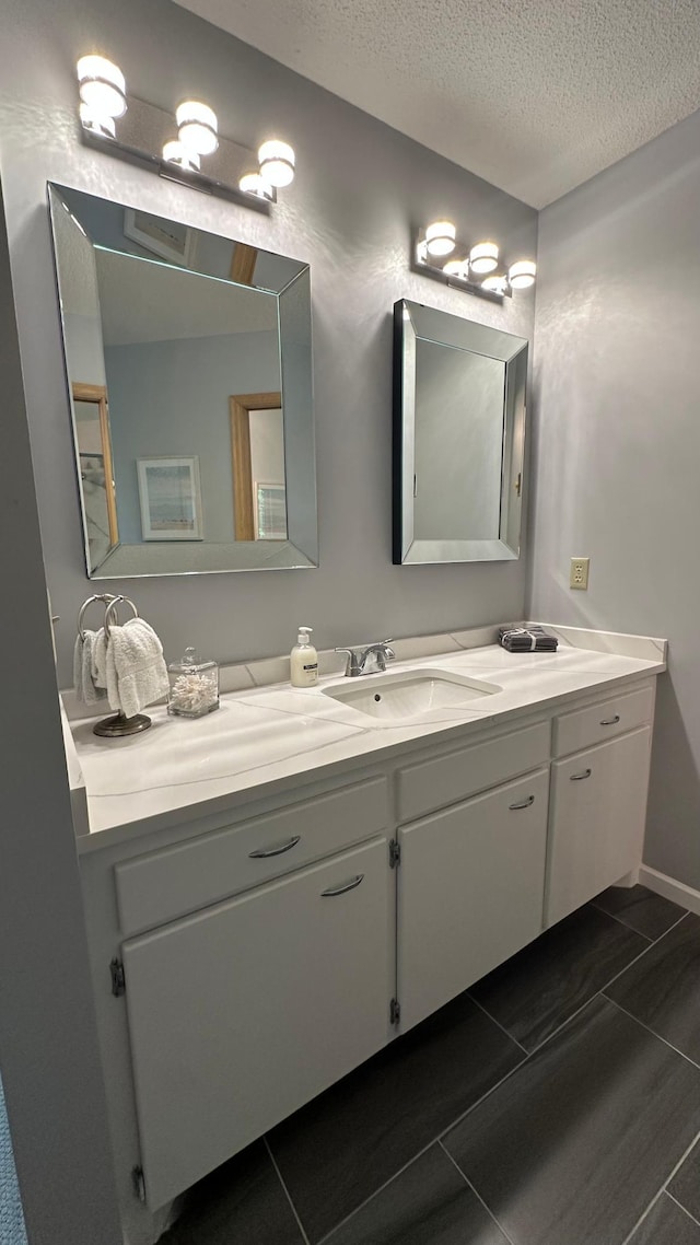 bathroom with a textured ceiling, vanity, and tile patterned flooring