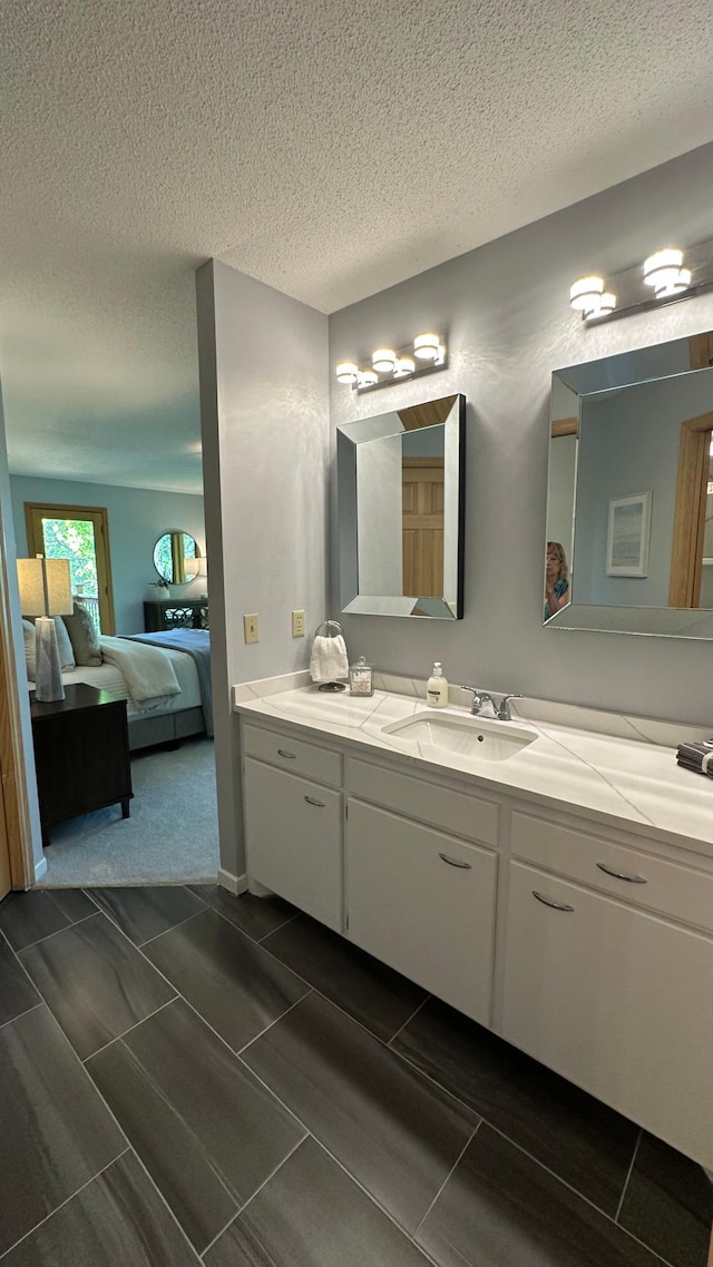 bathroom with ensuite bath, vanity, and a textured ceiling