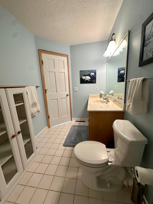 bathroom with toilet, a textured ceiling, vanity, and tile patterned flooring