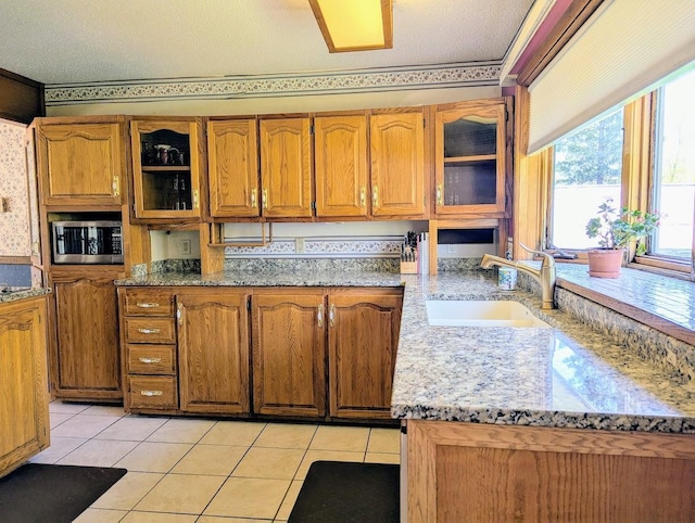 24944 State Highway 210, Mcgregor, MN 55760 - kitchen featuring stainless steel microwave, a sink, brown cabinetry, and glass insert cabinets