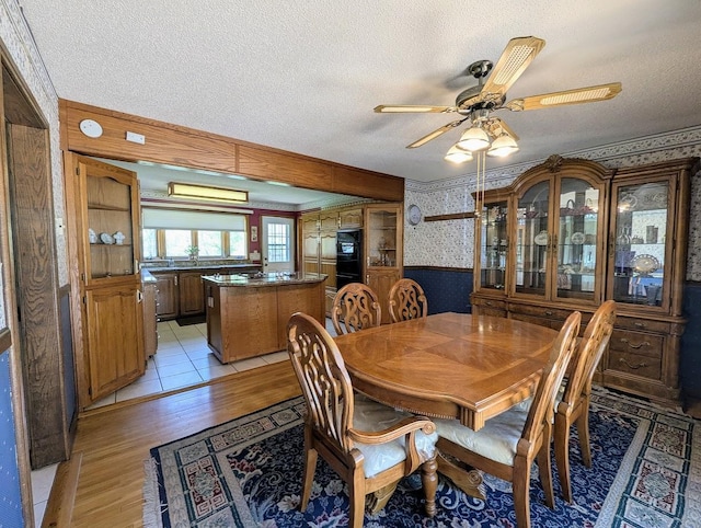 24944 State Highway 210, Mcgregor, MN 55760 - dining area featuring wallpapered walls, light wood-style flooring, a textured ceiling, ceiling fan, and wainscoting