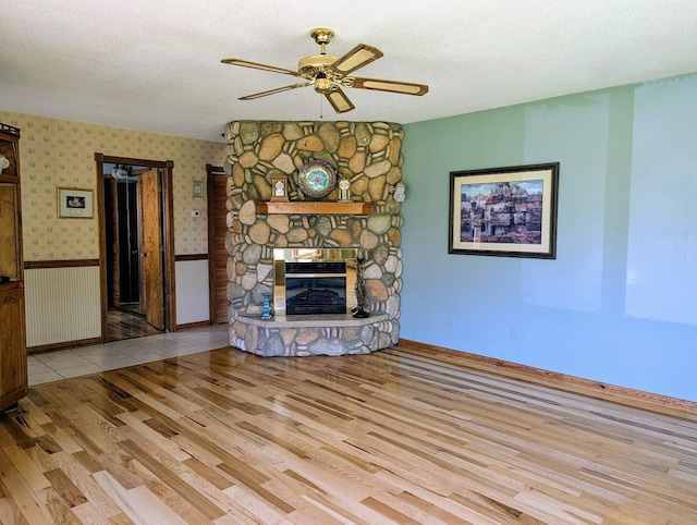 24944 State Highway 210, Mcgregor, MN 55760 - unfurnished living room with wood finished floors, a ceiling fan, a fireplace, a textured ceiling, and baseboards