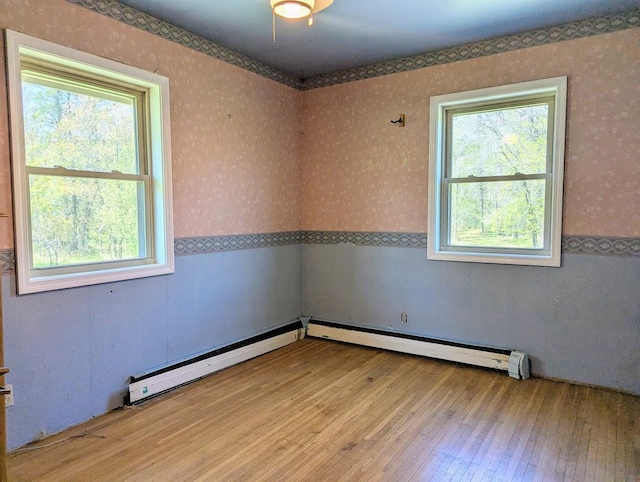 24944 State Highway 210, Mcgregor, MN 55760 - spare room with plenty of natural light, wood-type flooring, wallpapered walls, wainscoting, and a baseboard radiator