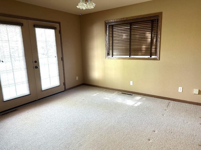 413 River Bluff Dr, Windom, MN 56101 - empty room featuring french doors, carpet flooring, baseboards, and a chandelier