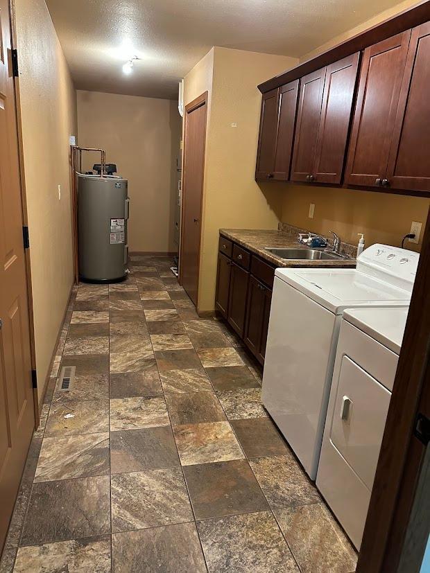 413 River Bluff Dr, Windom, MN 56101 - clothes washing area featuring water heater, cabinet space, washer and clothes dryer, and dark stone finish floors