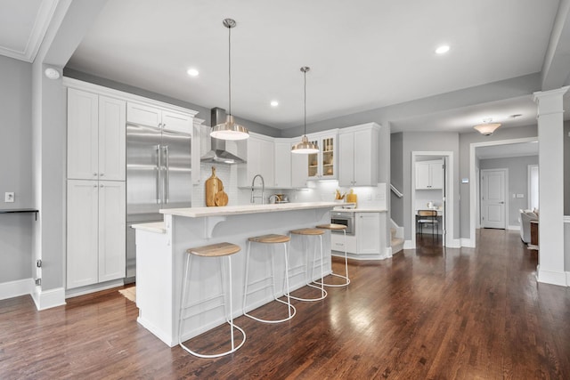 5220 Abbott Ave S, Minneapolis, MN 55410 - kitchen featuring wall chimney range hood, built in refrigerator, light countertops, tasteful backsplash, and white cabinets