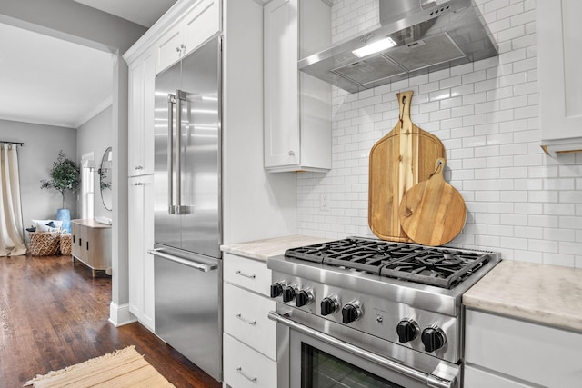 5220 Abbott Ave S, Minneapolis, MN 55410 - kitchen featuring premium appliances, wall chimney range hood, backsplash, dark wood-style flooring, and white cabinetry