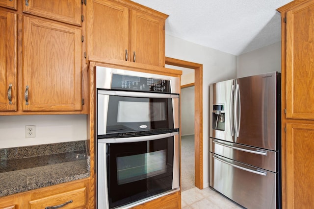 12005 27th Ave N, Plymouth, MN 55441 - kitchen featuring appliances with stainless steel finishes, brown cabinets, dark stone countertops, and a textured ceiling