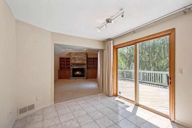 12005 27th Ave N, Plymouth, MN 55441 - spare room featuring rail lighting, a textured ceiling, a brick fireplace, light carpet, and baseboards