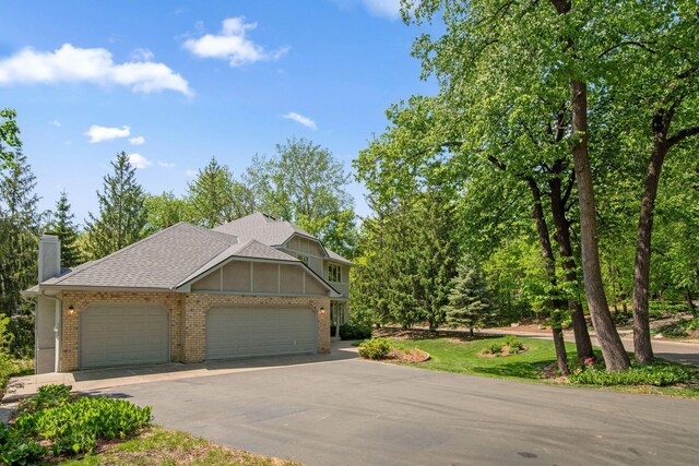 12005 27th Ave N, Plymouth, MN 55441 - view of front facade with brick siding, driveway, an attached garage, a shingled roof, and a chimney