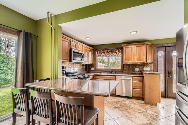 15947 Scandia Trl N, Scandia, MN 55073 - kitchen with stainless steel appliances, a sink, decorative backsplash, a kitchen breakfast bar, and dark stone countertops