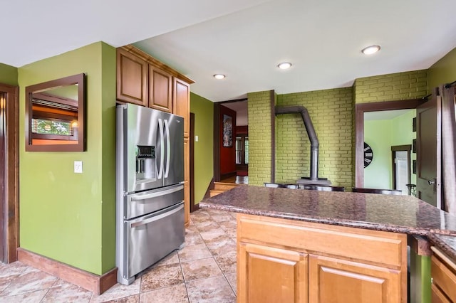 15947 Scandia Trl N, Scandia, MN 55073 - kitchen with stainless steel refrigerator with ice dispenser, a wood stove, brick wall, baseboards, and light tile patterned floors