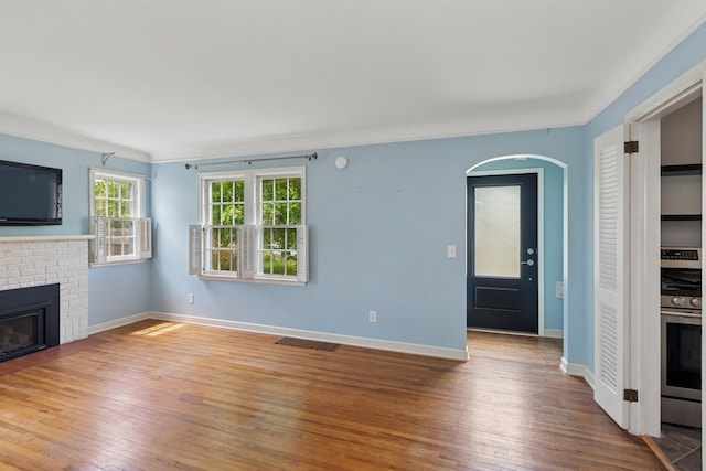 4150 Beard Ave N, Robbinsdale, MN 55422 - unfurnished living room with wood finished floors, a brick fireplace, and arched walkways