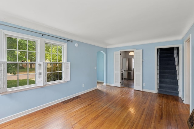 4150 Beard Ave N, Robbinsdale, MN 55422 - unfurnished room featuring arched walkways, wood-type flooring, and stairway