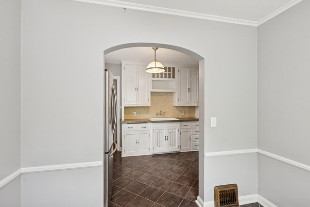 4150 Beard Ave N, Robbinsdale, MN 55422 - kitchen featuring white cabinetry, freestanding refrigerator, decorative backsplash, arched walkways, and dark tile patterned floors