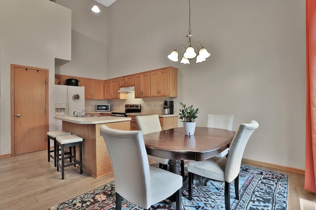 2171 Cleveland Way S, Cambridge, MN 55008 - dining room featuring a high ceiling, a chandelier, light wood-style floors, and baseboards