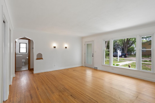 3122 Arthur St NE, Minneapolis, MN 55418 - unfurnished living room featuring arched walkways, light wood finished floors, and baseboards