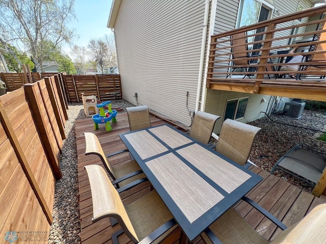 deck with outdoor dining space, fence, and cooling unit