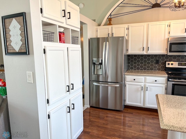 kitchen with appliances with stainless steel finishes, dark wood finished floors, white cabinets, tasteful backsplash, and light stone counters