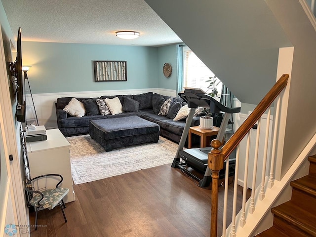 living area with wood finished floors, a textured ceiling, and stairway
