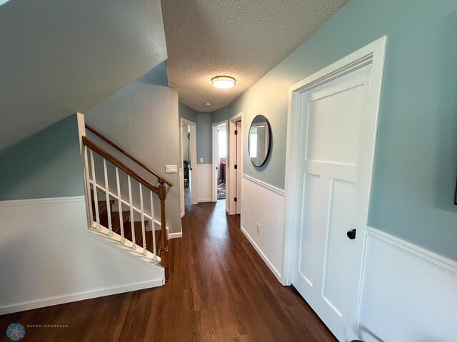 foyer with a textured ceiling, wood finished floors, and stairs