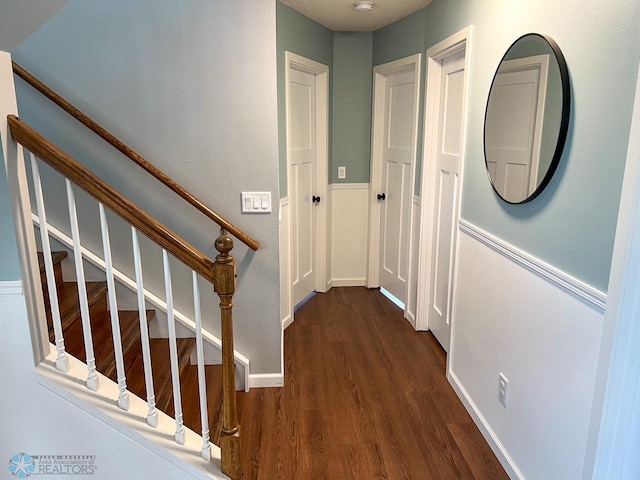 hallway featuring dark wood-style flooring, stairway, and baseboards